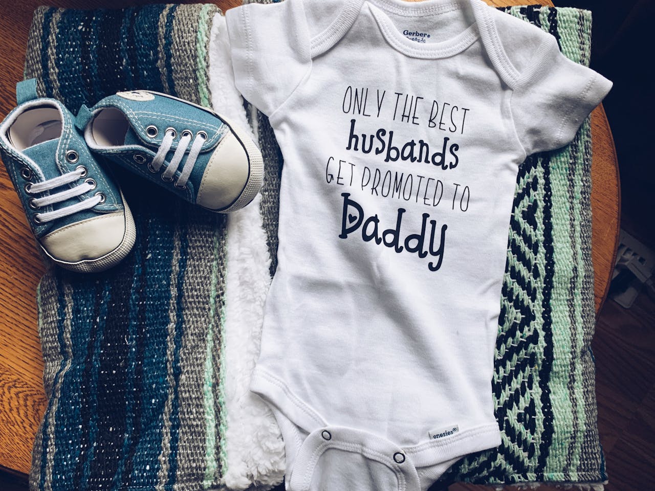 Baby onesie with shoes and blankets featuring the text 'Only the Best Husbands Get Promoted to Daddy.'