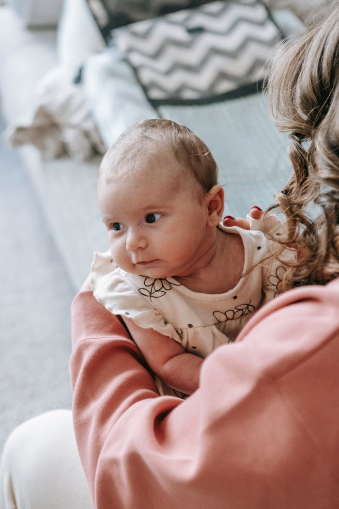 Adorable baby cradled in mother's arms, exhibiting a loving bond indoors.